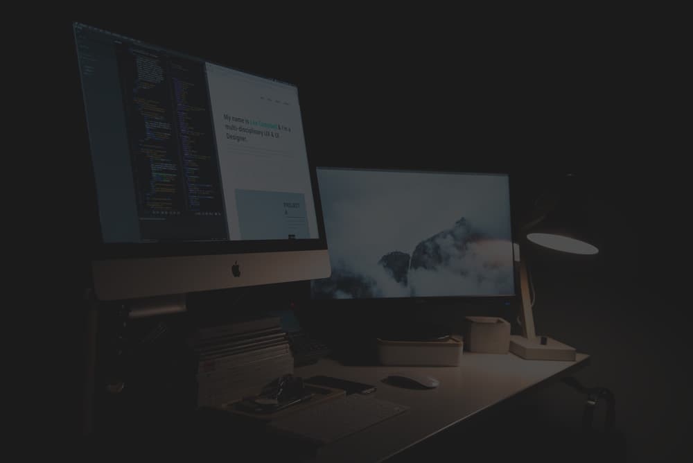 Arbeitsplatz mit Design und Programmcode auf zwei Bildschirmen